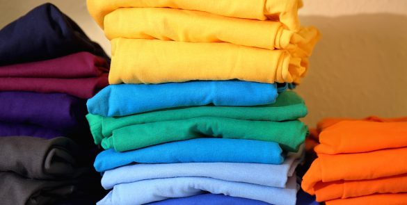 Stacks of colorful t-shirts prepared for printing on shelf